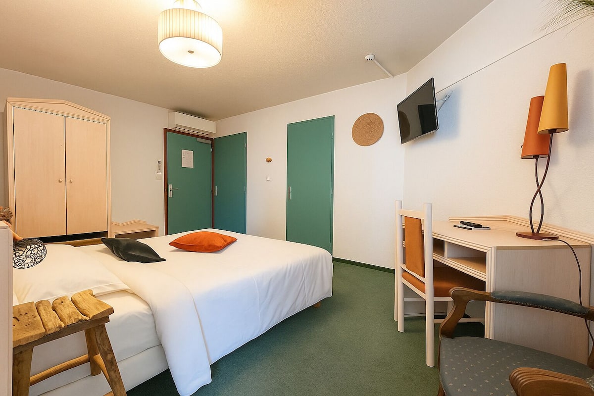 Ein Schlafzimmer mit Bett, Schreibtisch, Stuhl, Kleiderschrank und Fernseher an der Wand.