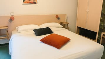 Un letto rifatto con lenzuola bianche e un cuscino arancione, un comodino in legno con una lampada, un armadio e un quadro appeso al muro.