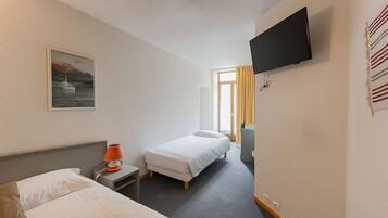 Ein Hotelzimmer mit zwei Betten, einem Fernseher, einem Gemälde und einem Fenster mit Vorhängen.