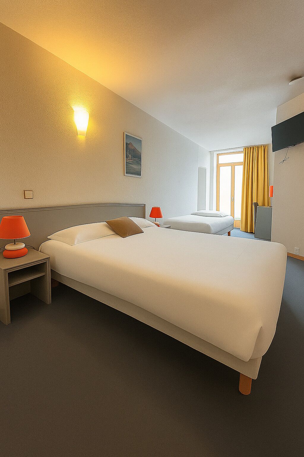 A hotel room with a large bed, two bedside tables, a wall-mounted TV, and a window with curtains.