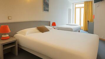 A hotel room with a large bed, two bedside tables, a wall-mounted TV, and a window with curtains.