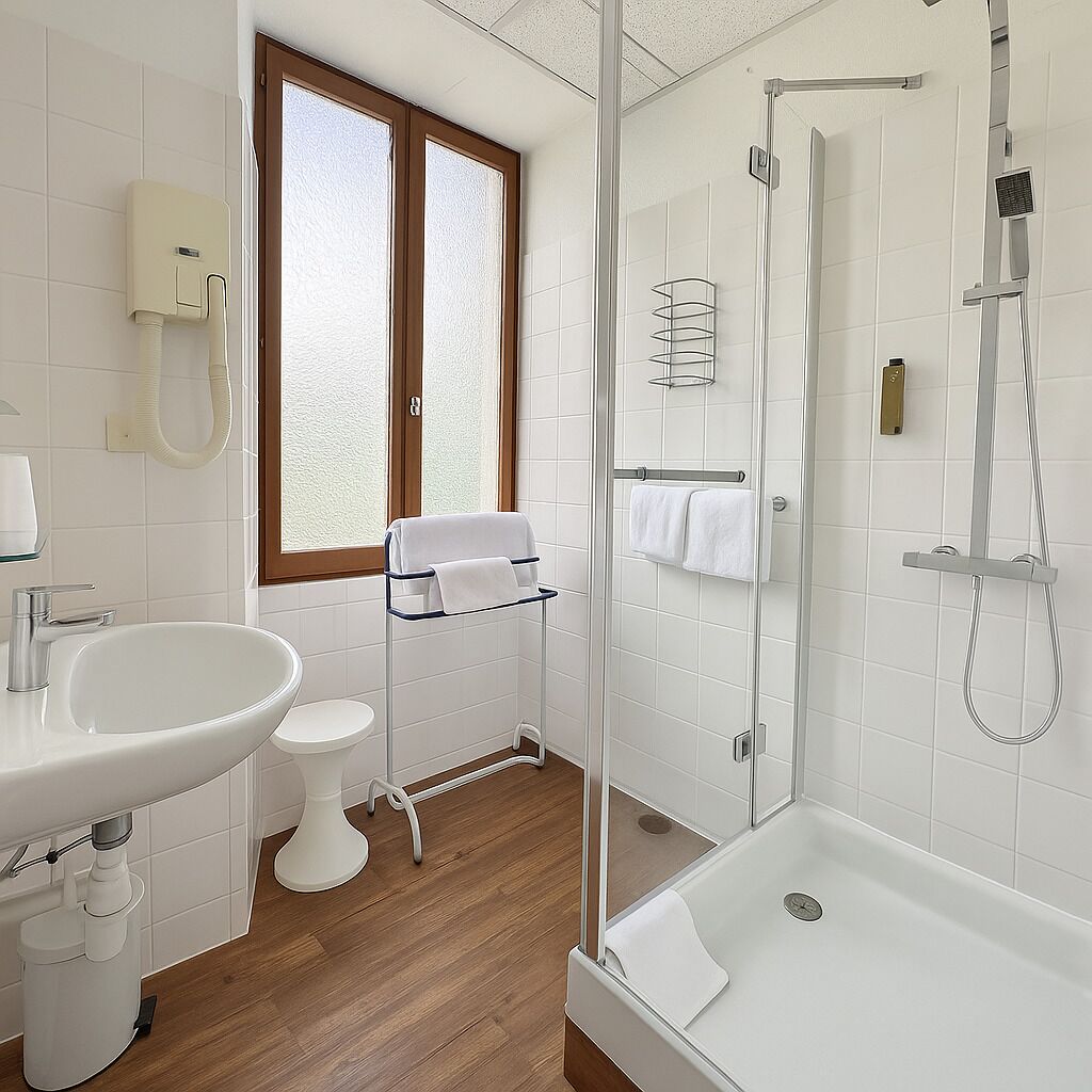 Een moderne badkamer met een douchecabine van glas, een witte wastafel, toilet en een raam met gezandstraald glas.