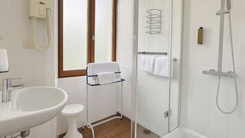Een moderne badkamer met een douchecabine van glas, een witte wastafel, toilet en een raam met gezandstraald glas.