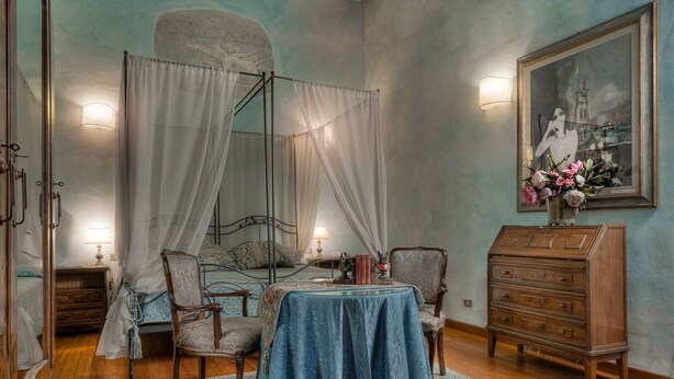 Une pièce comprenant un lit, une table, des chaises, une commode et un tableau accroché au mur.