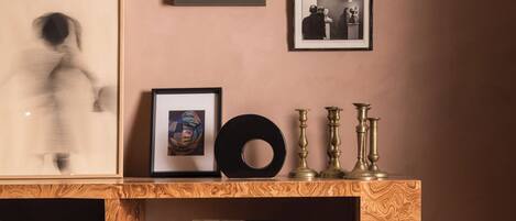 Una habitación con una estantería de madera, cuadros enmarcados y una lámpara fijada a la pared.