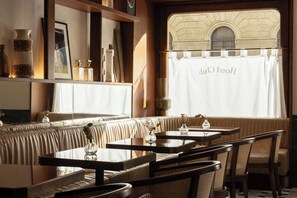 A cozy restaurant with wooden furniture, a cushioned bench seating area, and a view through a window with a curtain displaying "Hotel Cluj". - c-hotels Club (Florence)