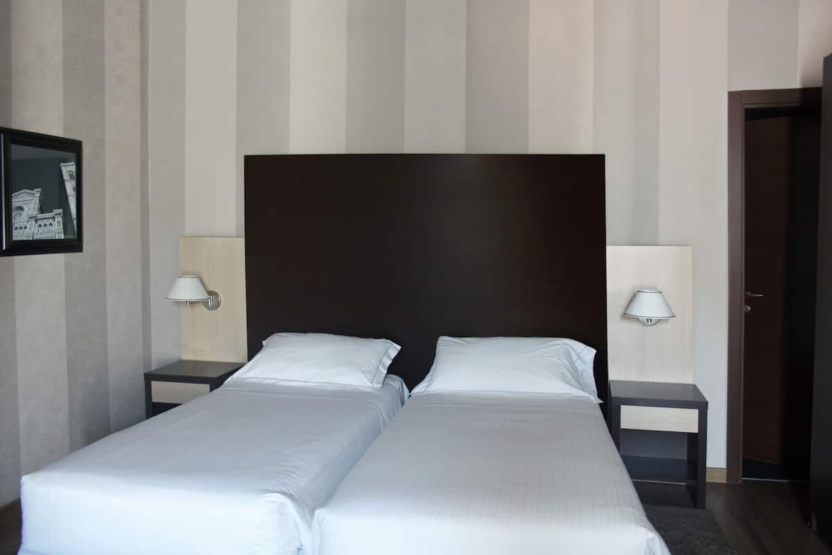 A double bed with a dark headboard, two bedside tables with lamps, and a framed picture on the wall.