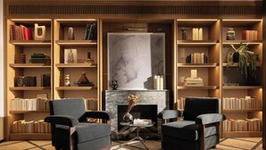 A cozy living room with two armchairs, a fireplace, and bookshelves filled with books and decorative items. - c-hotels Club (Florence)