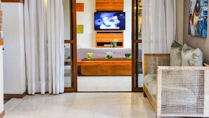 Una sala de estar con televisor, un sofá, una mesa de centro y un cuadro decorativo.