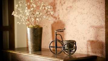 A metal bicycle and a potted plant on a wooden surface against a textured wall.