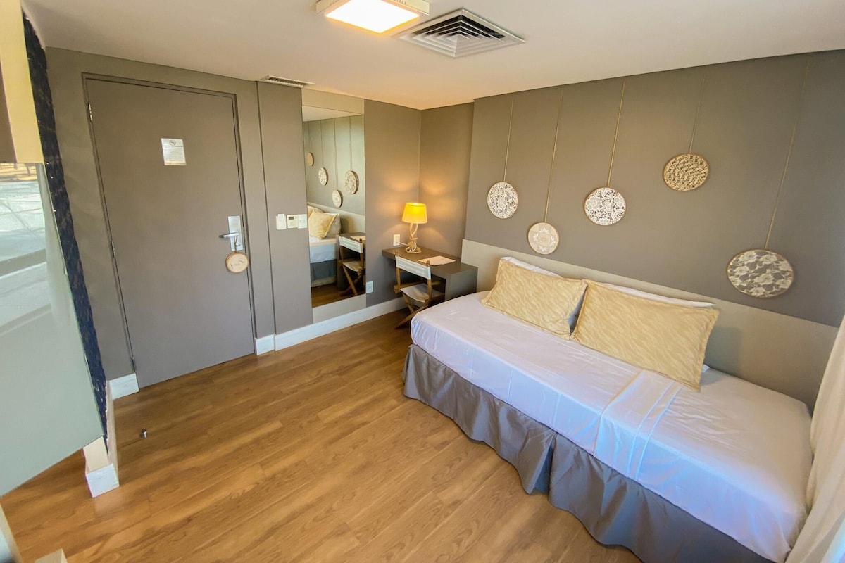 A bedroom with a bed, bedside table, lamp, and decorative wall art.