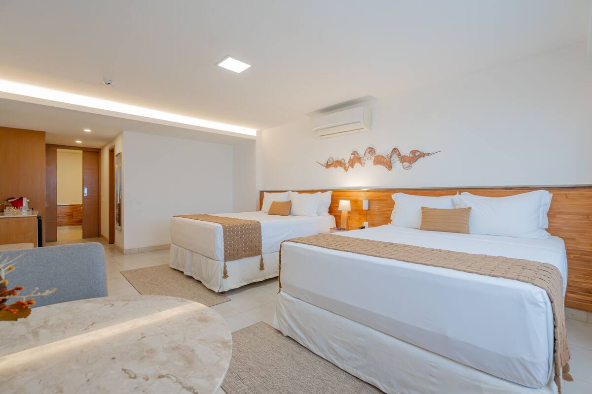 A hotel room with two beds, a desk, and a chair.