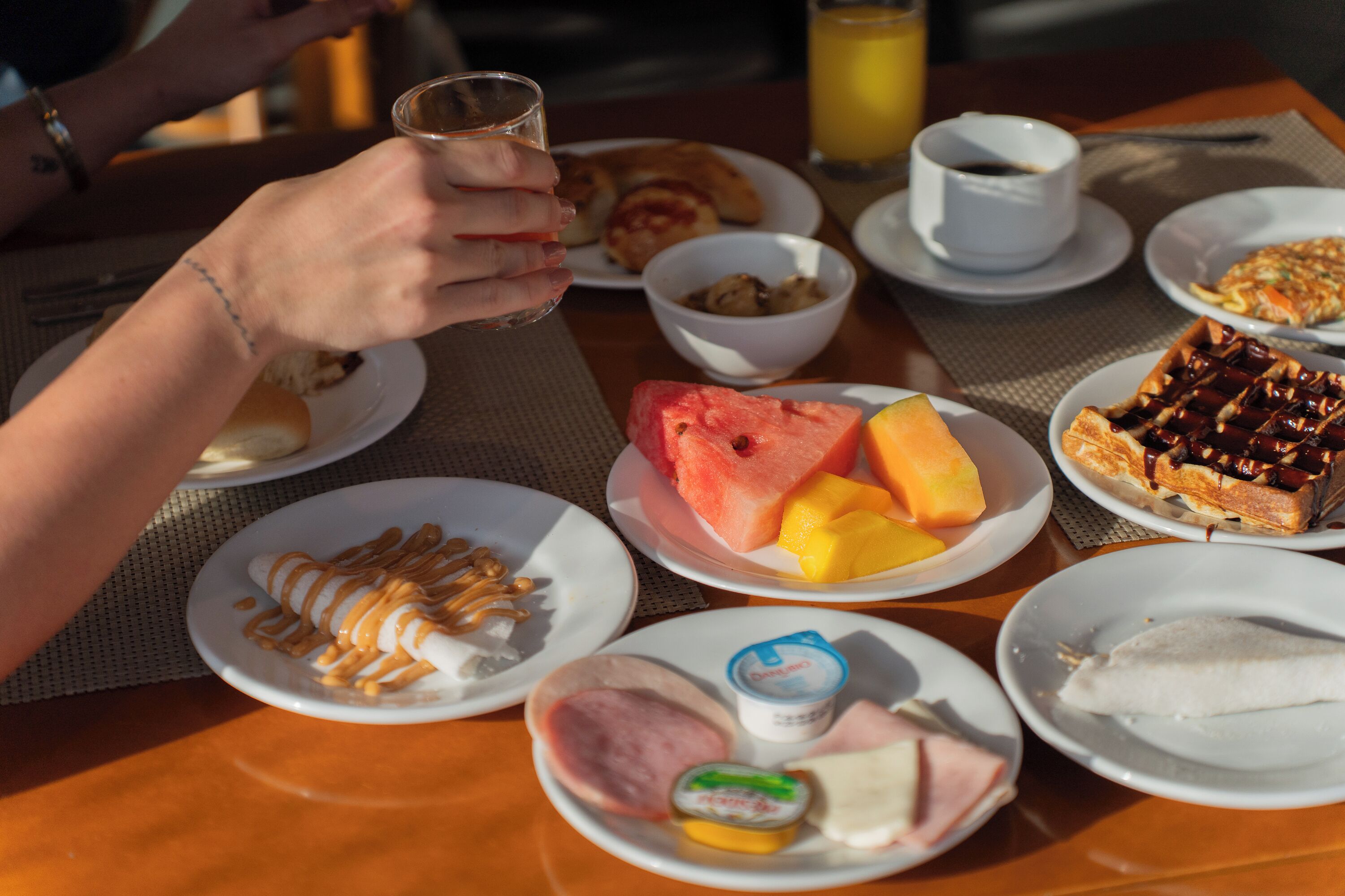 A breakfast table with plates of food, a glass of juice, and a cup of coffee.