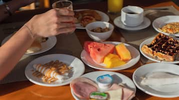 A breakfast table with plates of food, a glass of juice, and a cup of coffee.