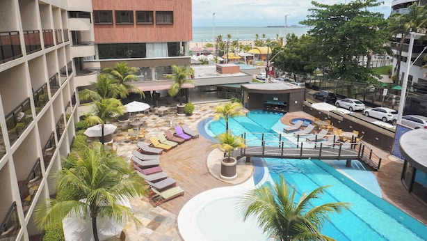 A hotel with a rooftop pool, lounge chairs, and a view of the ocean. - Afago Mareiro Hotel (Fortaleza)