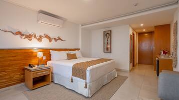 Habitación de hotel con una cama grande, mesita de noche, lámpara y aire acondicionado instalado en la pared.
