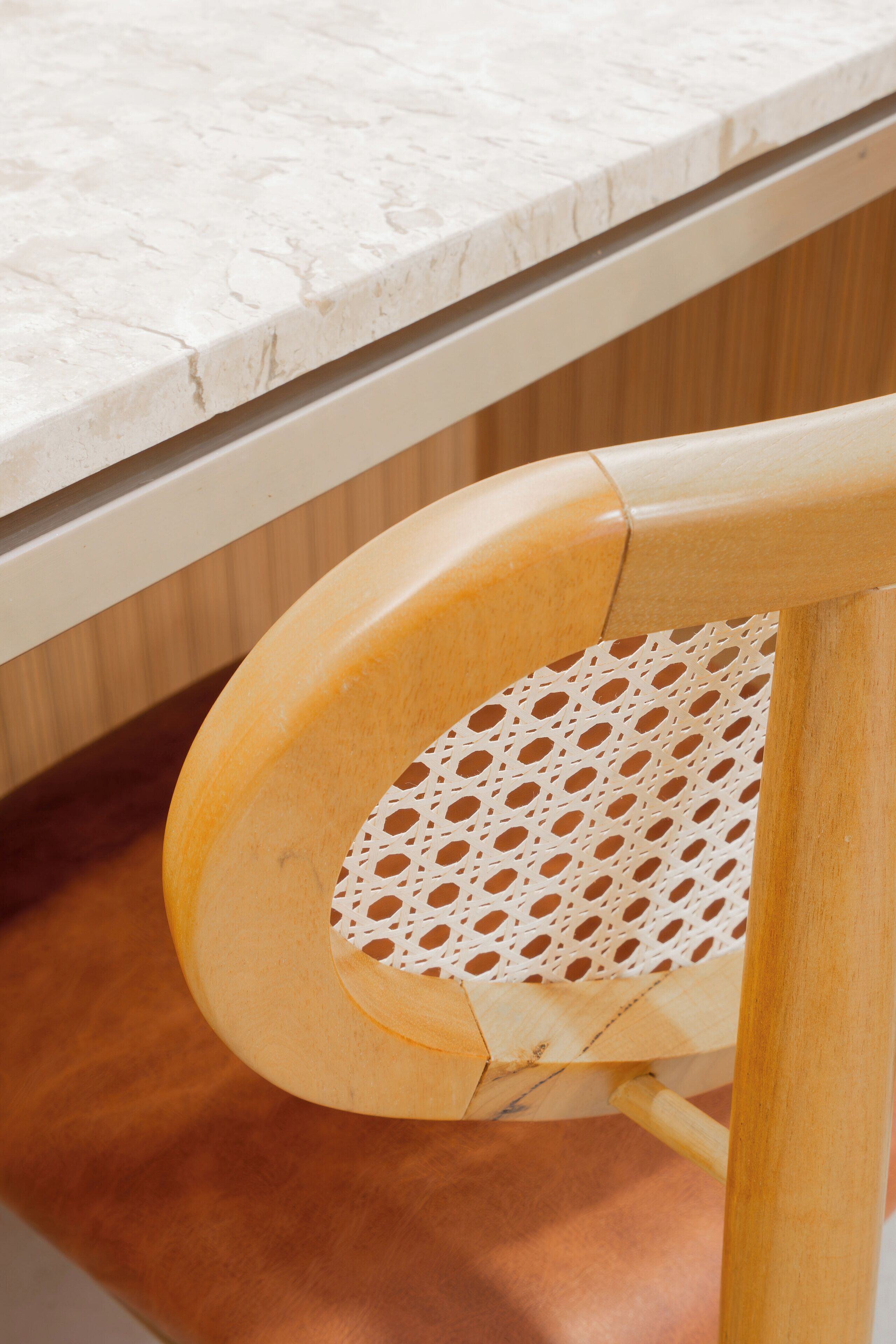 A wooden chair with a woven seat and a white countertop in the background.