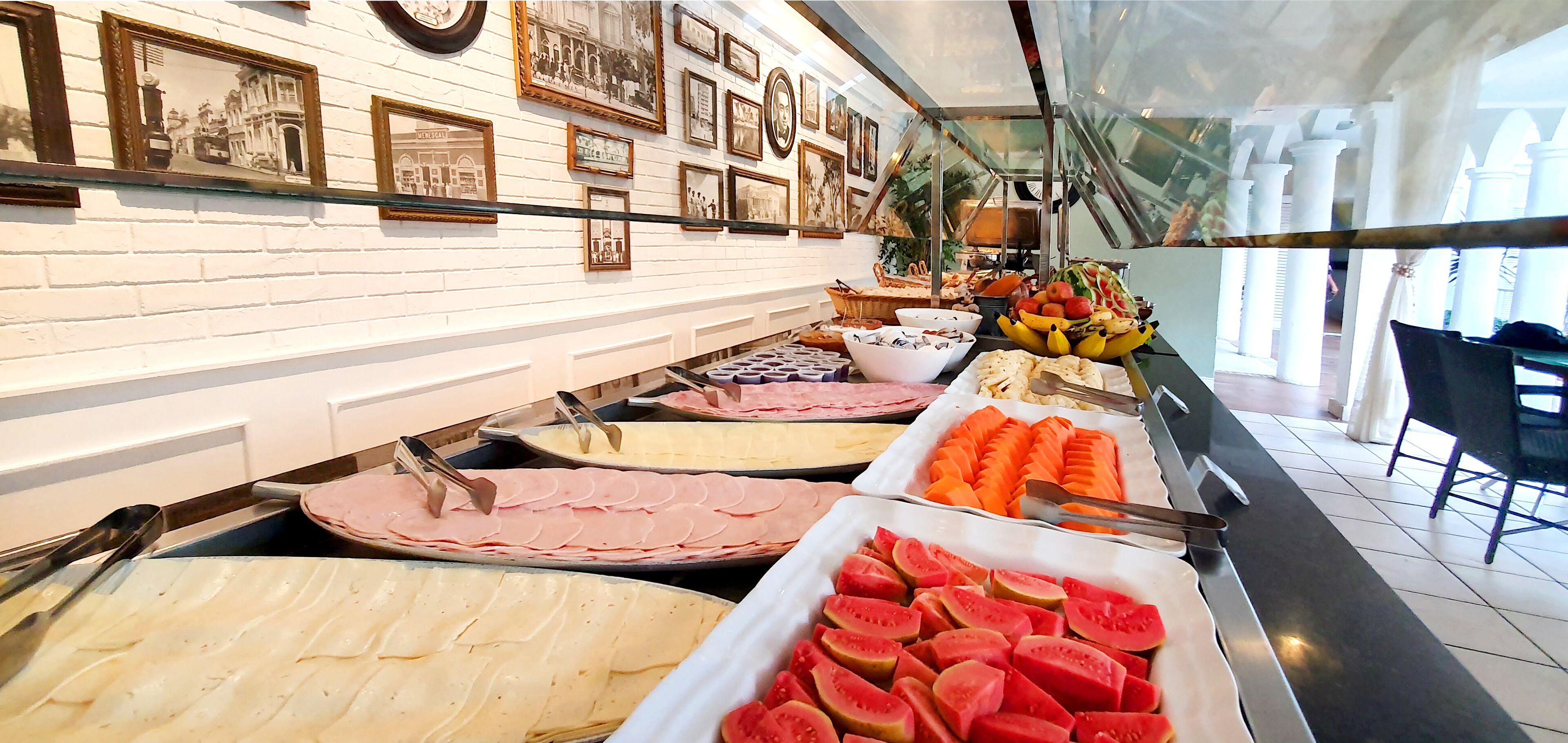 A buffet with various food options, including sliced meats, cheeses, and fruits.