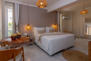 A bedroom with a large bed, bedside tables, a wooden dining table, and wicker lamps.