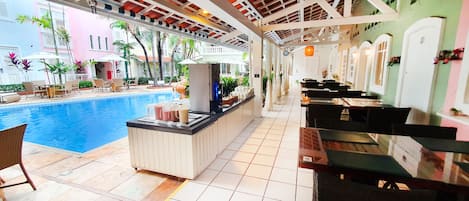 Zona de bar junto a la piscina, con mostrador, sillas y mesas.