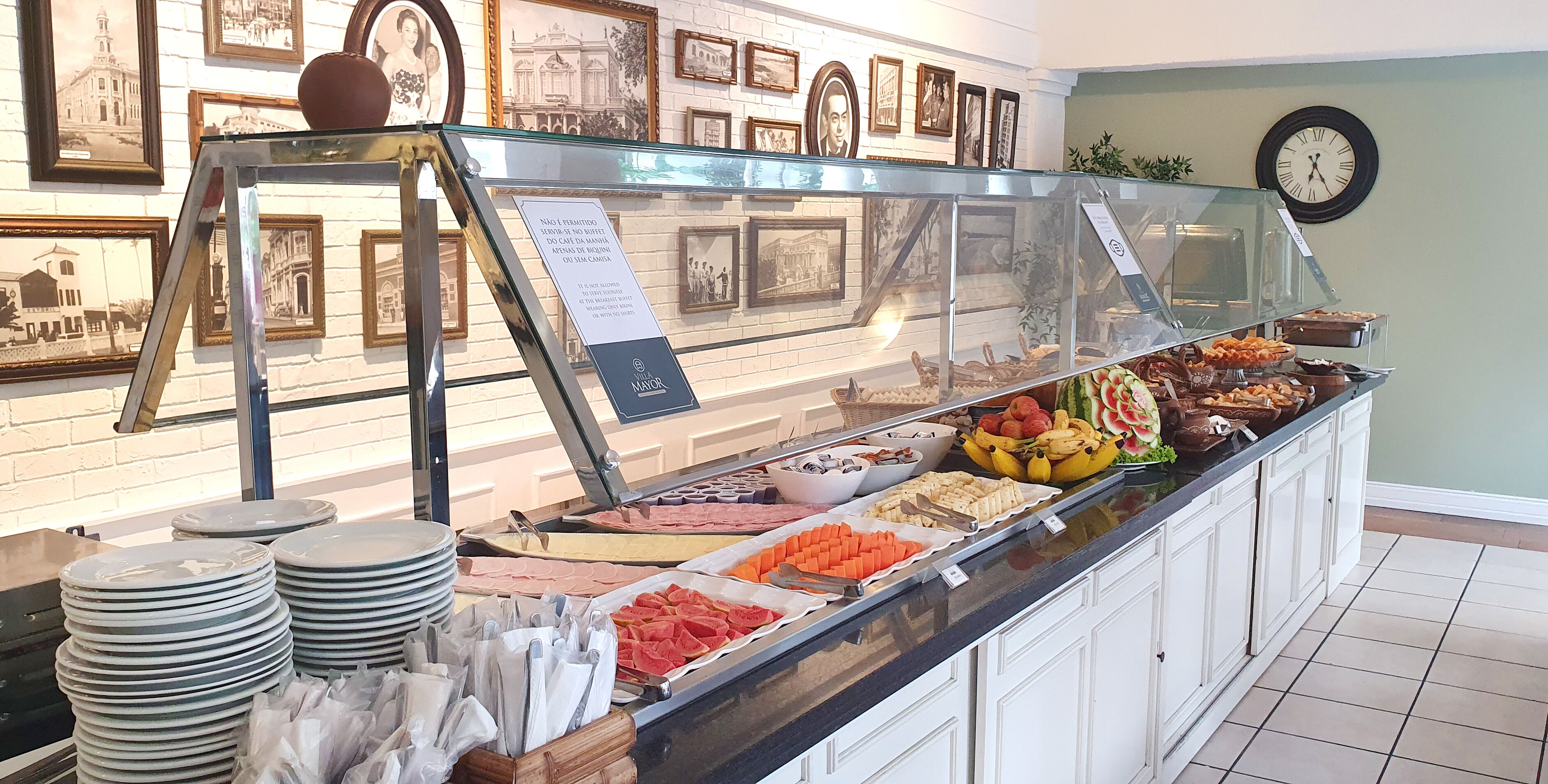 Een buffet met verschillende gerechten, een glazen vitrine en een muur met ingelijste foto's.