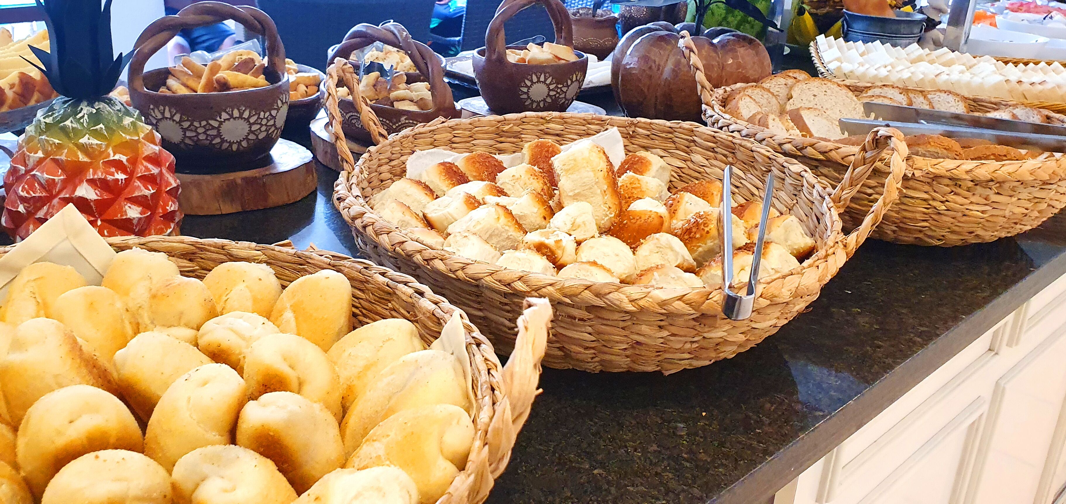 Un bufé con diferentes panes y pasteles expuestos en cestas de mimbre.
