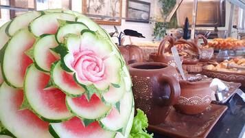 A watermelon carved into a rose with a teapot and bread on a table.