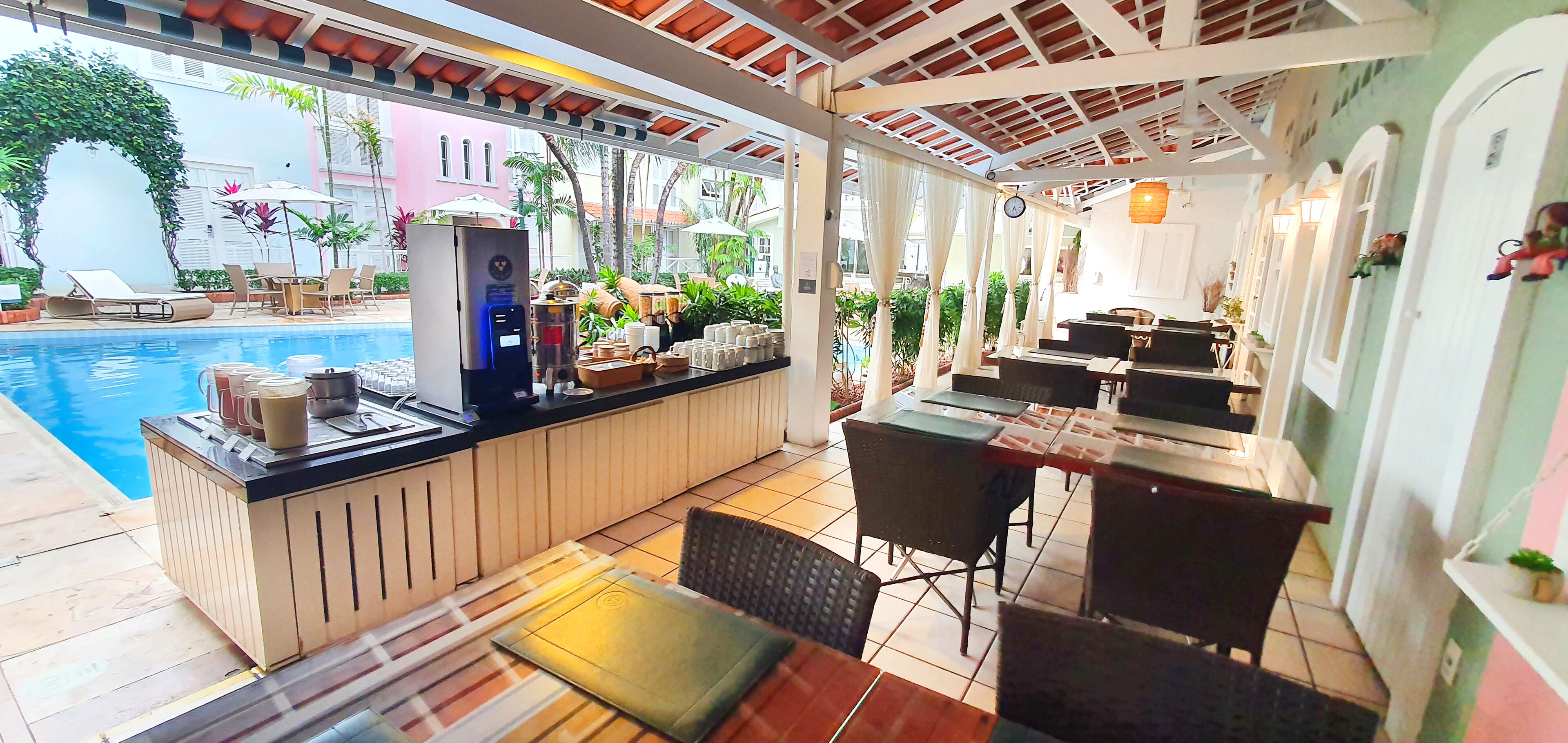 Uma área de bar à beira da piscina, com assentos e um refrigerador.