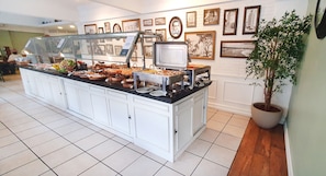 A buffet area with various food items, a television, and framed pictures on the wall.