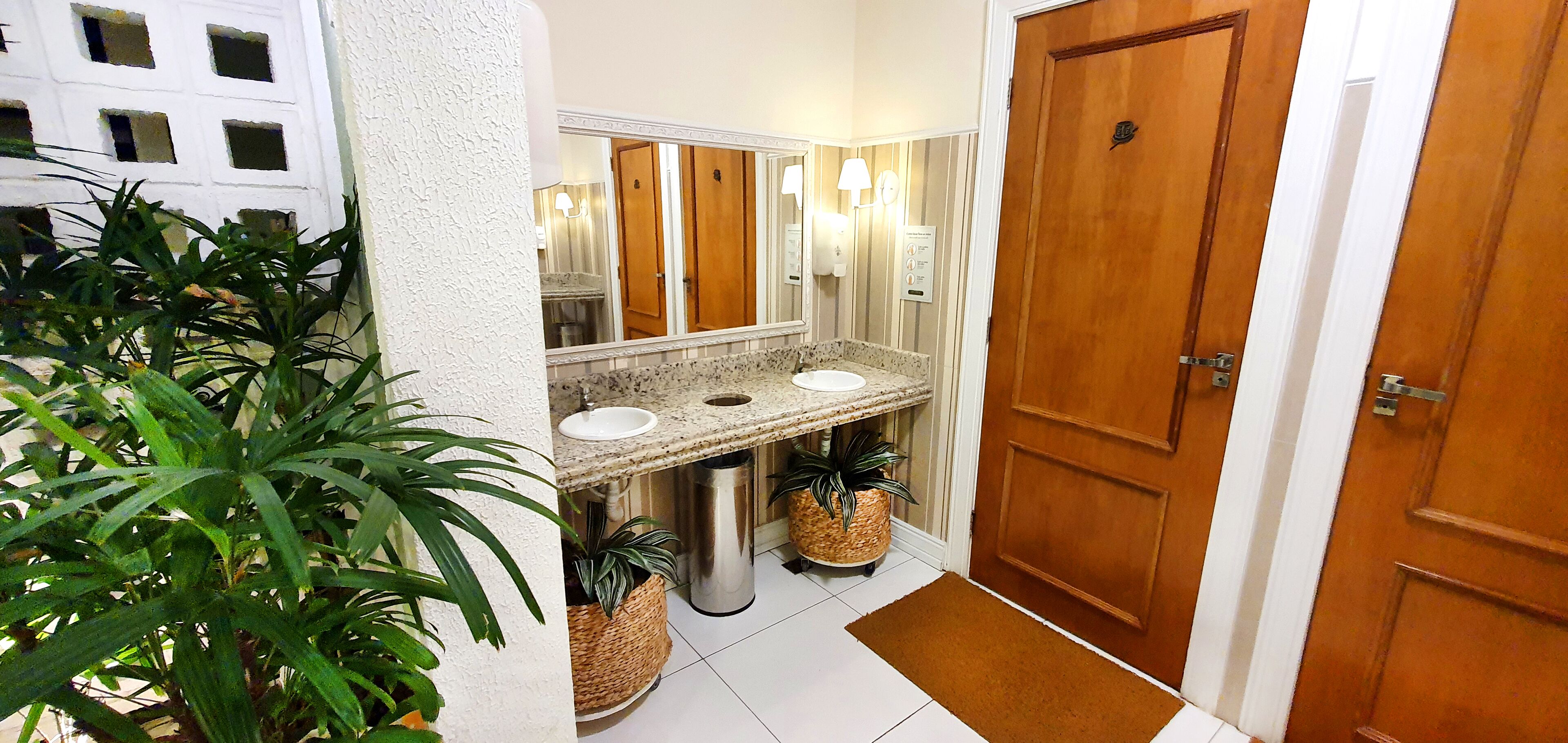 Un baño con dos lavamanos, un espejo y una puerta de madera.