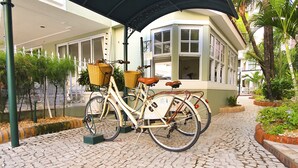 Un vélo ancien, doté de paniers, est garé sur un chemin pavé de pierres.