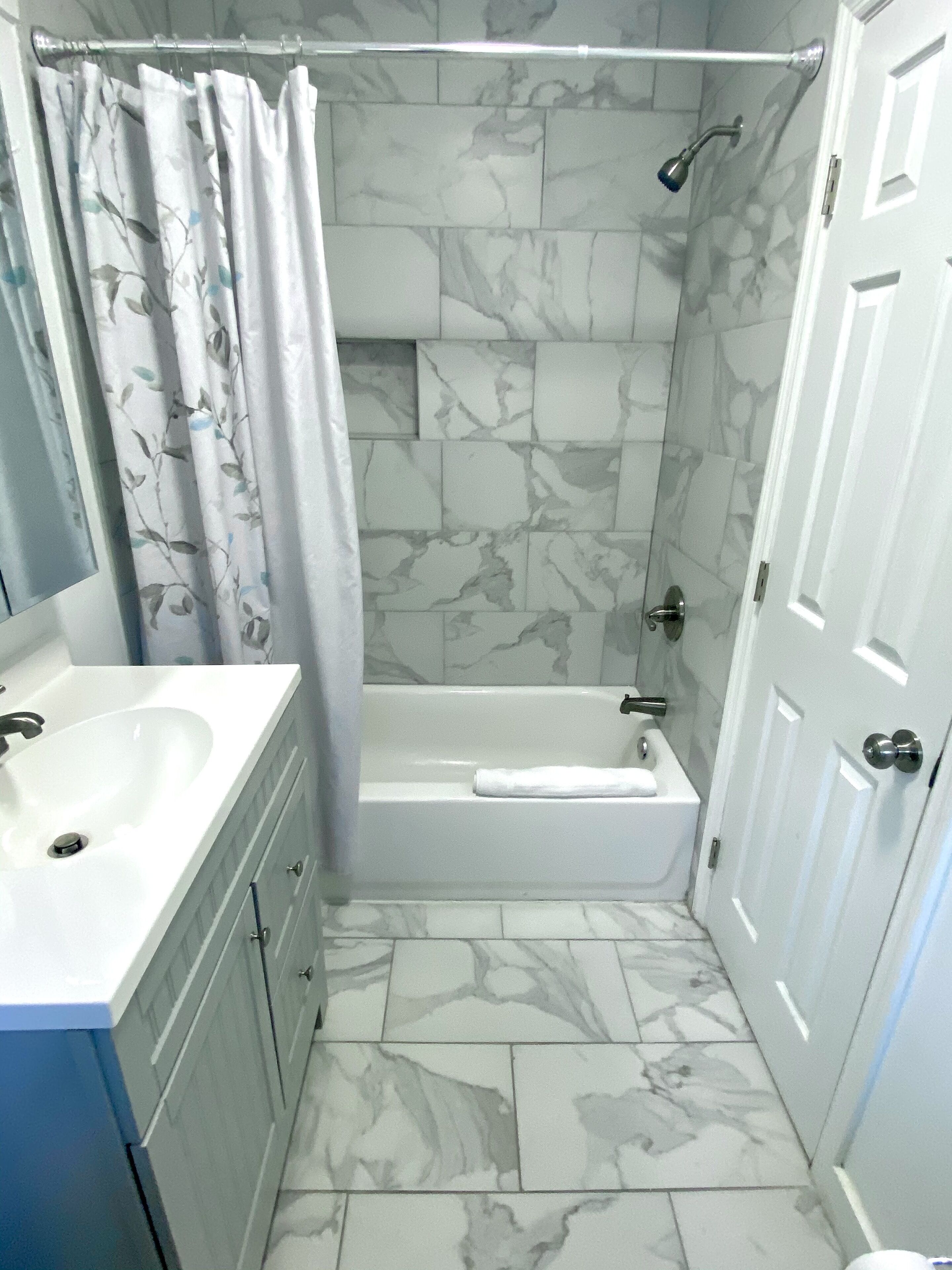 Une salle de bain avec une baignoire, une douche, un lavabo et un miroir.