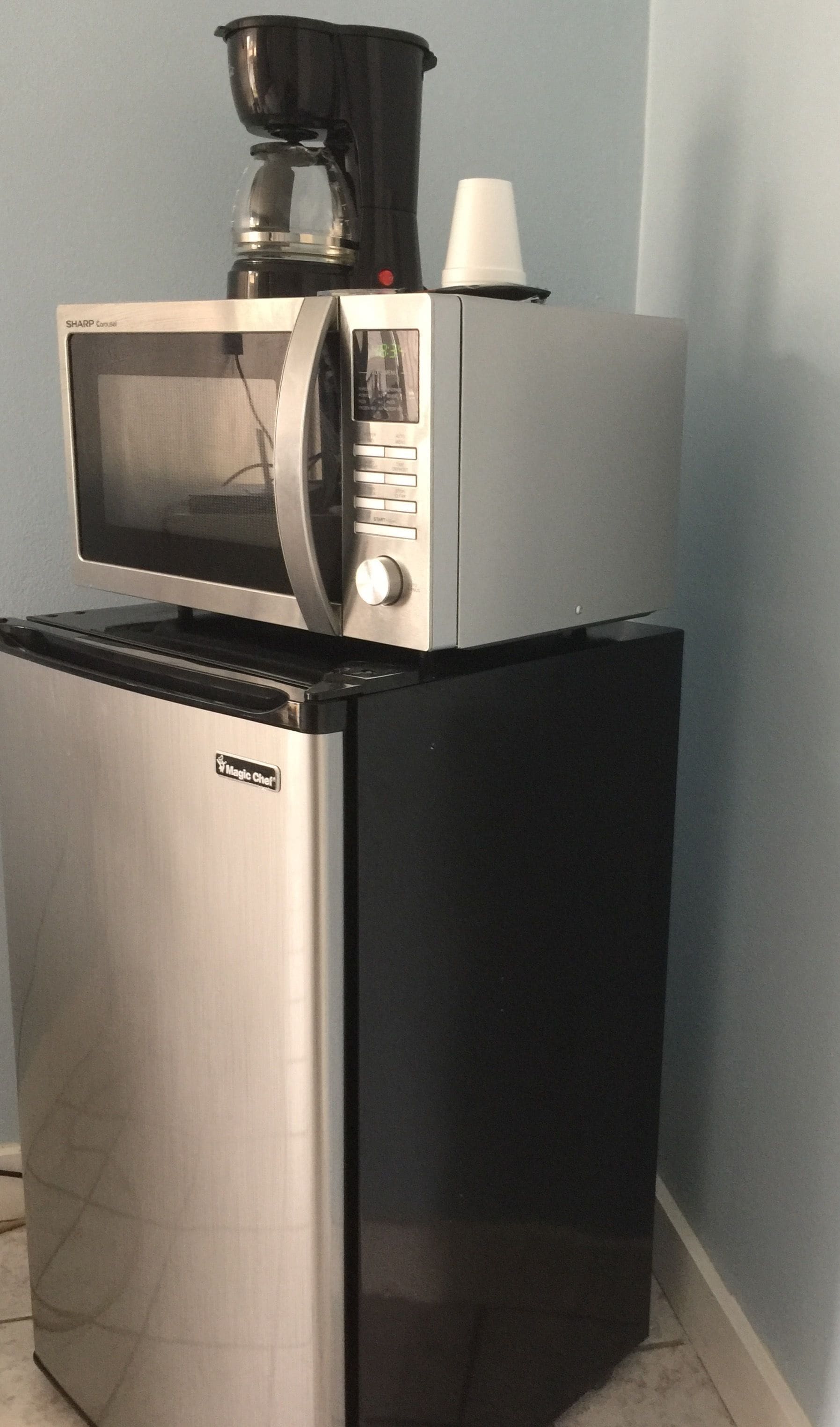 A compact refrigerator with a built-in microwave on top.