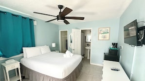 A hotel room with a bed, a desk, a ceiling fan, a TV, and a bathroom visible through an open door. - The St Maurice Beach Inn (Hollywood)