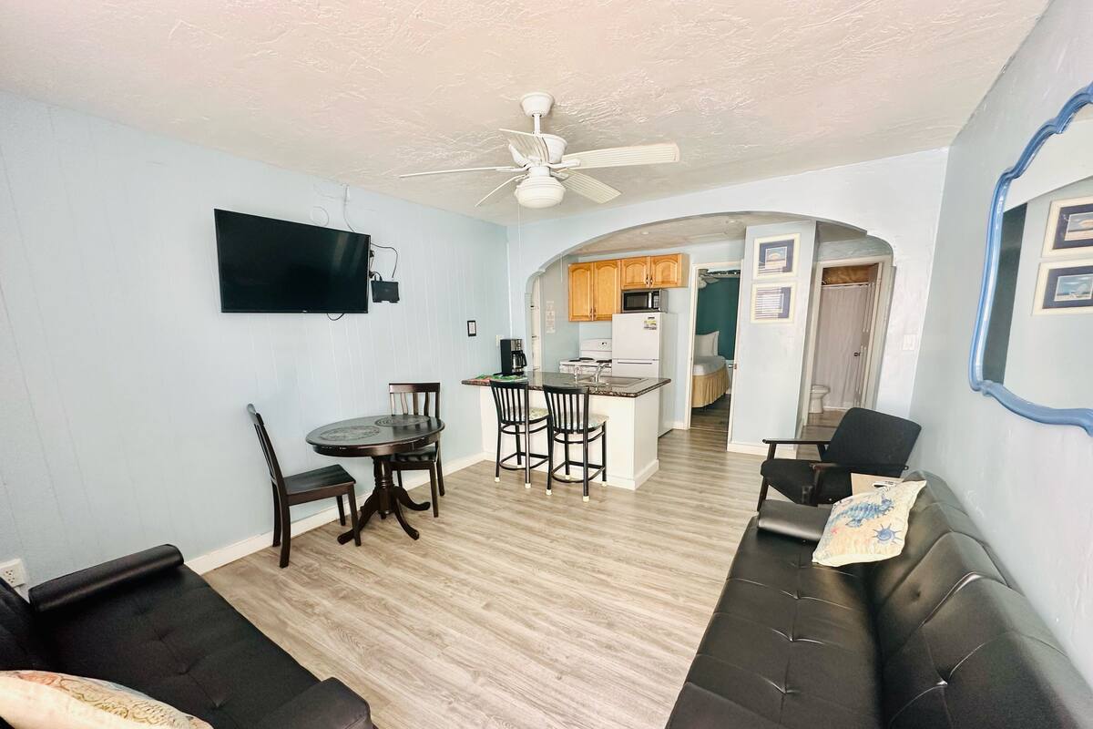 A compact living space with a dining area, kitchenette, and a sofa.