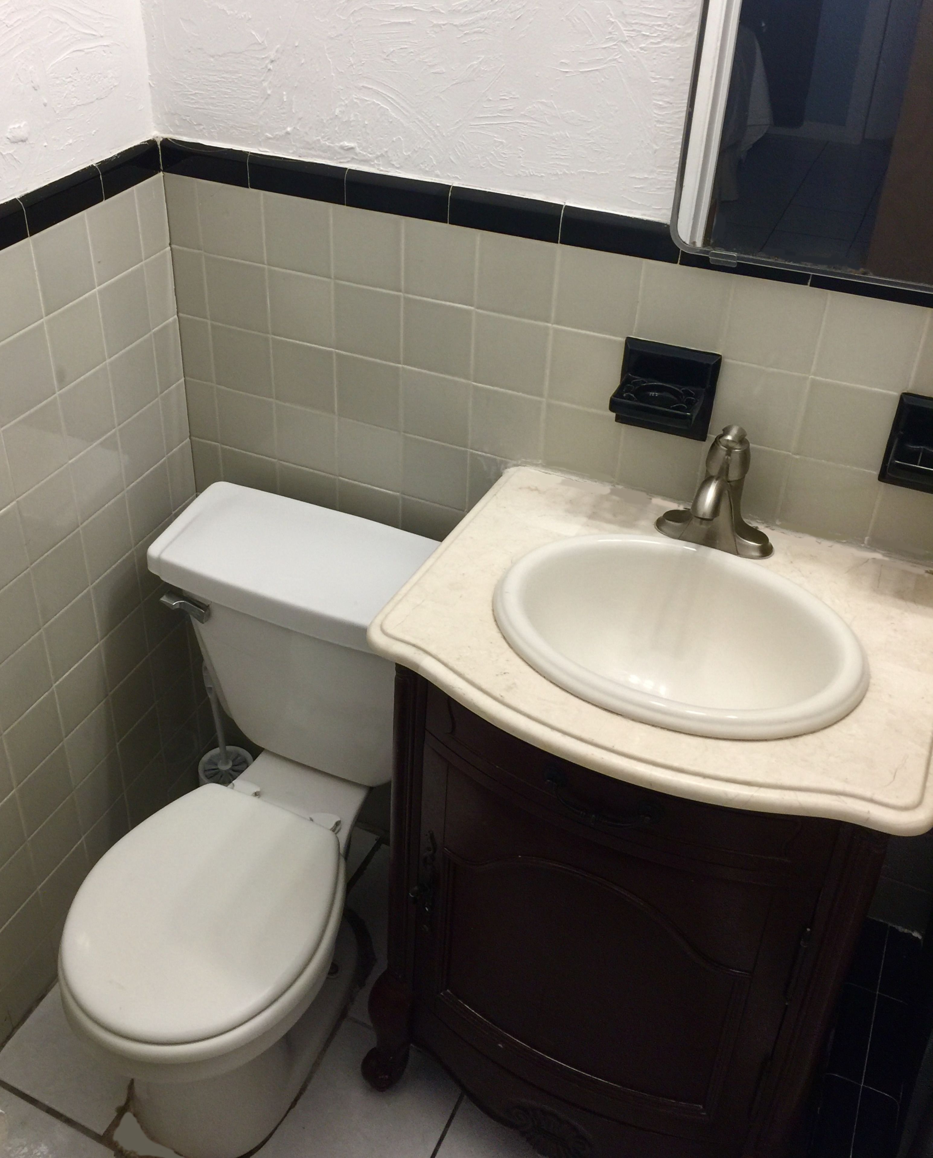 Un bagno con il water, un lavandino e uno specchio.