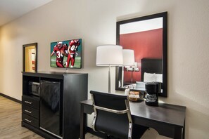 Une chambre d’hôtel équipée d’un bureau, d’une télévision, d’une machine à café et d’un miroir.