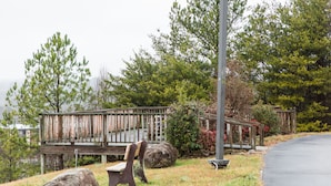 A wooden deck with a bench, surrounded by rocks and trees.
