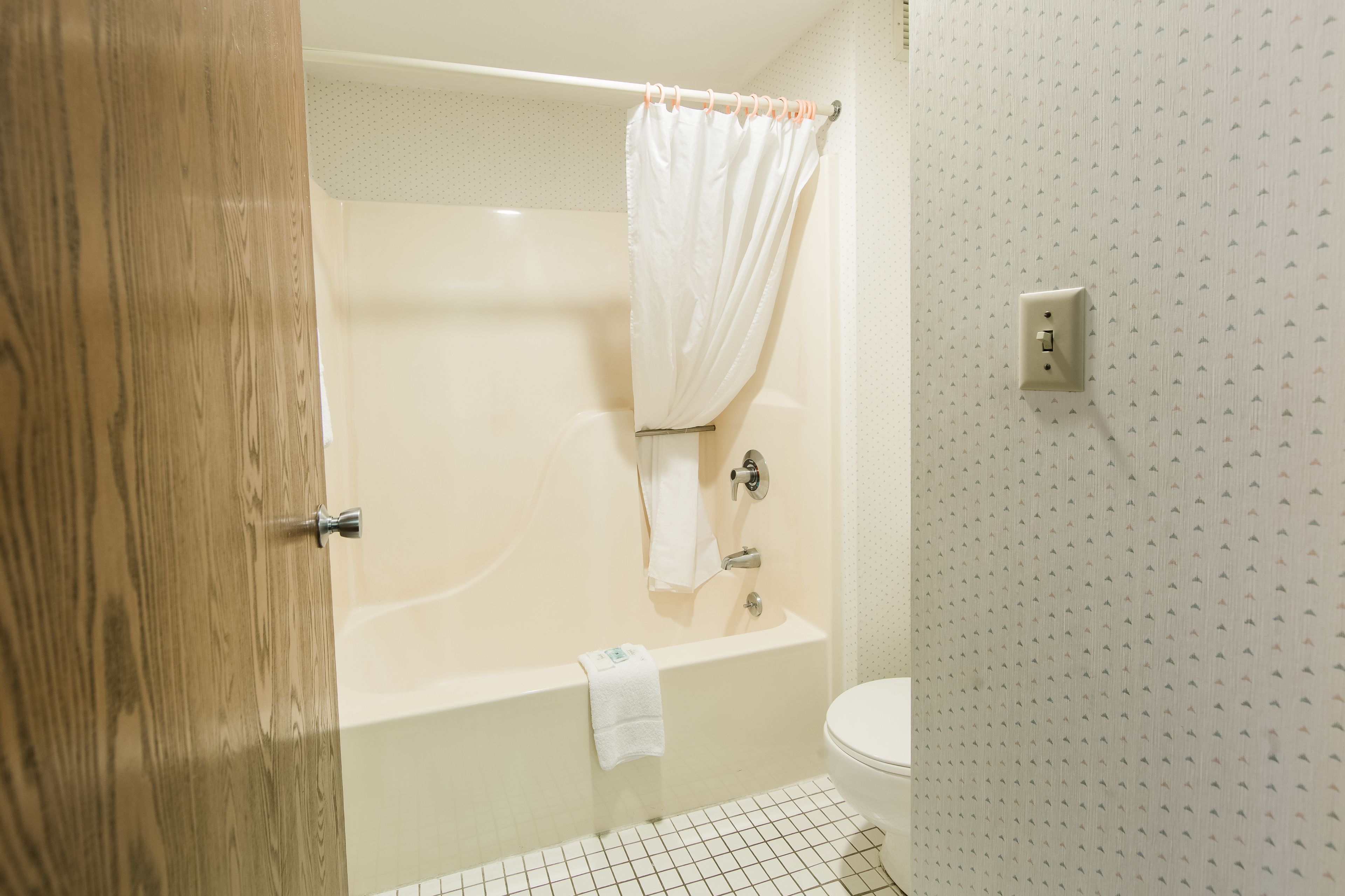 A bathroom with a bathtub, a toilet, and a shower curtain.