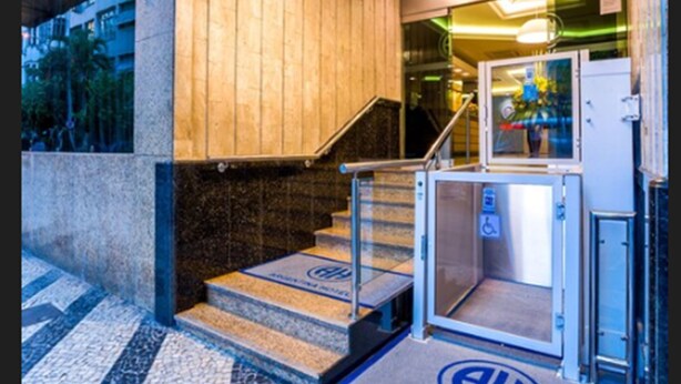 A hotel entrance with a marble staircase, a glass elevator, and a sign indicating the entrance.