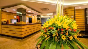 A reception area with a reception desk, a large floral arrangement, and a clock on the wall.
