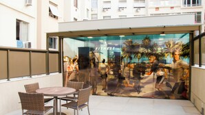 Restaurante con sillas de mimbre y una pared de vidrio que muestra una exposición de una tienda de artículos deportivos.