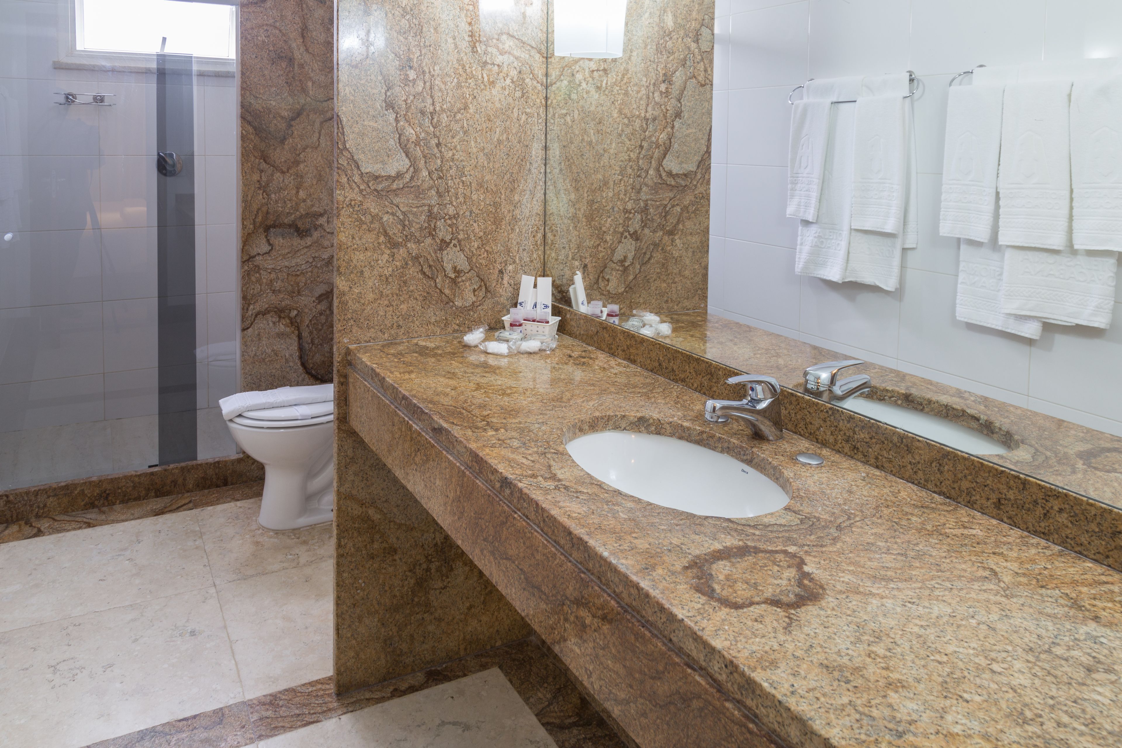 Une salle de bain avec un comptoir en marbre, un lavabo, un miroir et des toilettes.