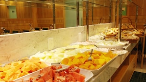 Un bufé con diversas frutas y pasteles.