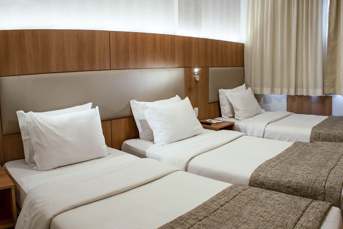 Una habitación de hotel con dos camas, cabeceros de madera, una mesita de noche y un televisor.