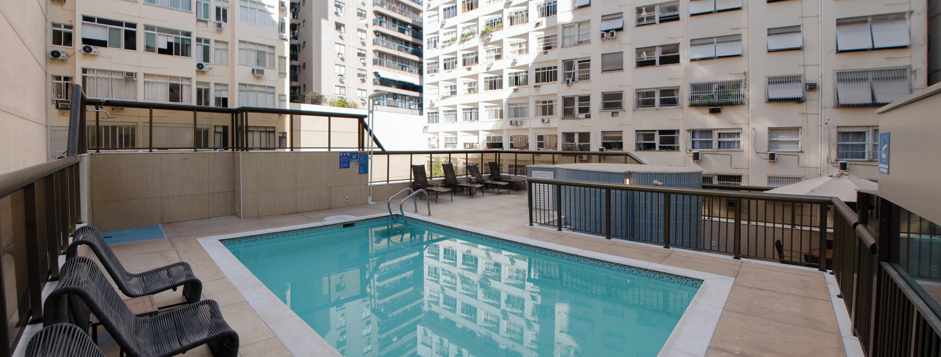 Una piscina al aire libre, sombrillas, sillones reclinables de piscina