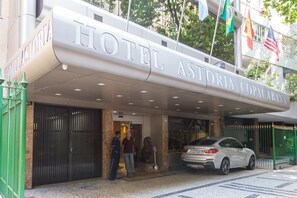 L’entrée d’un hôtel, avec une grande enseigne indiquant « HÔTEL ASTORIA COPACABANA ».