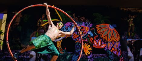 A performer in a green outfit manipulating a hula hoop.