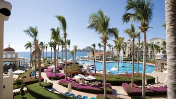 A resort with a large pool, palm trees, and a view of the ocean.