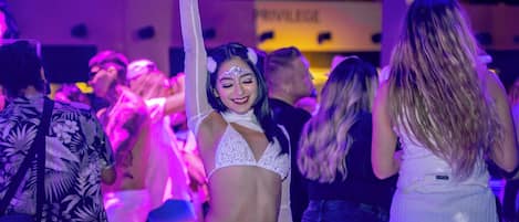 A crowded indoor venue with people dancing and socializing.